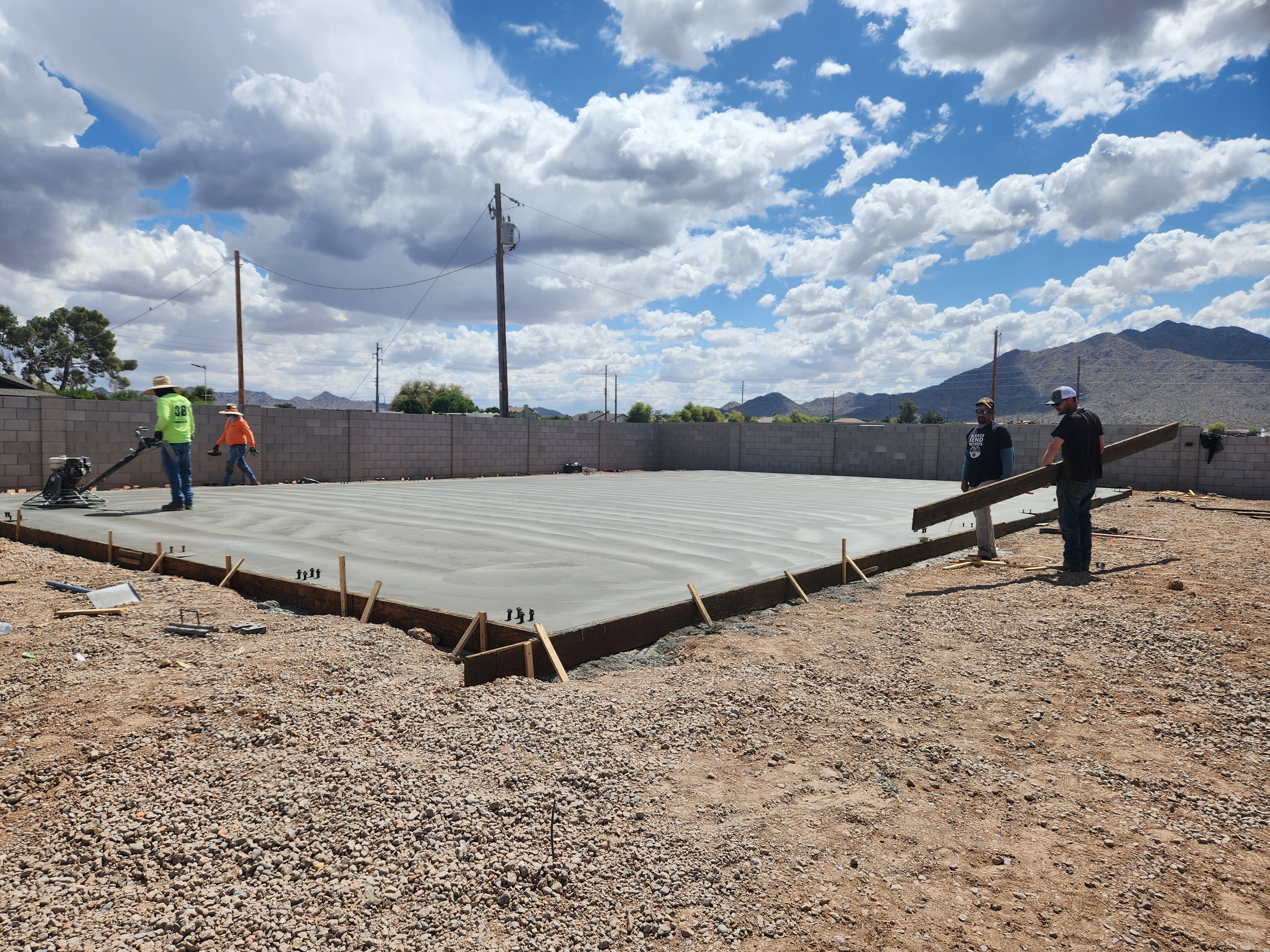Showing workers finishing the cement for a steel building's foundation