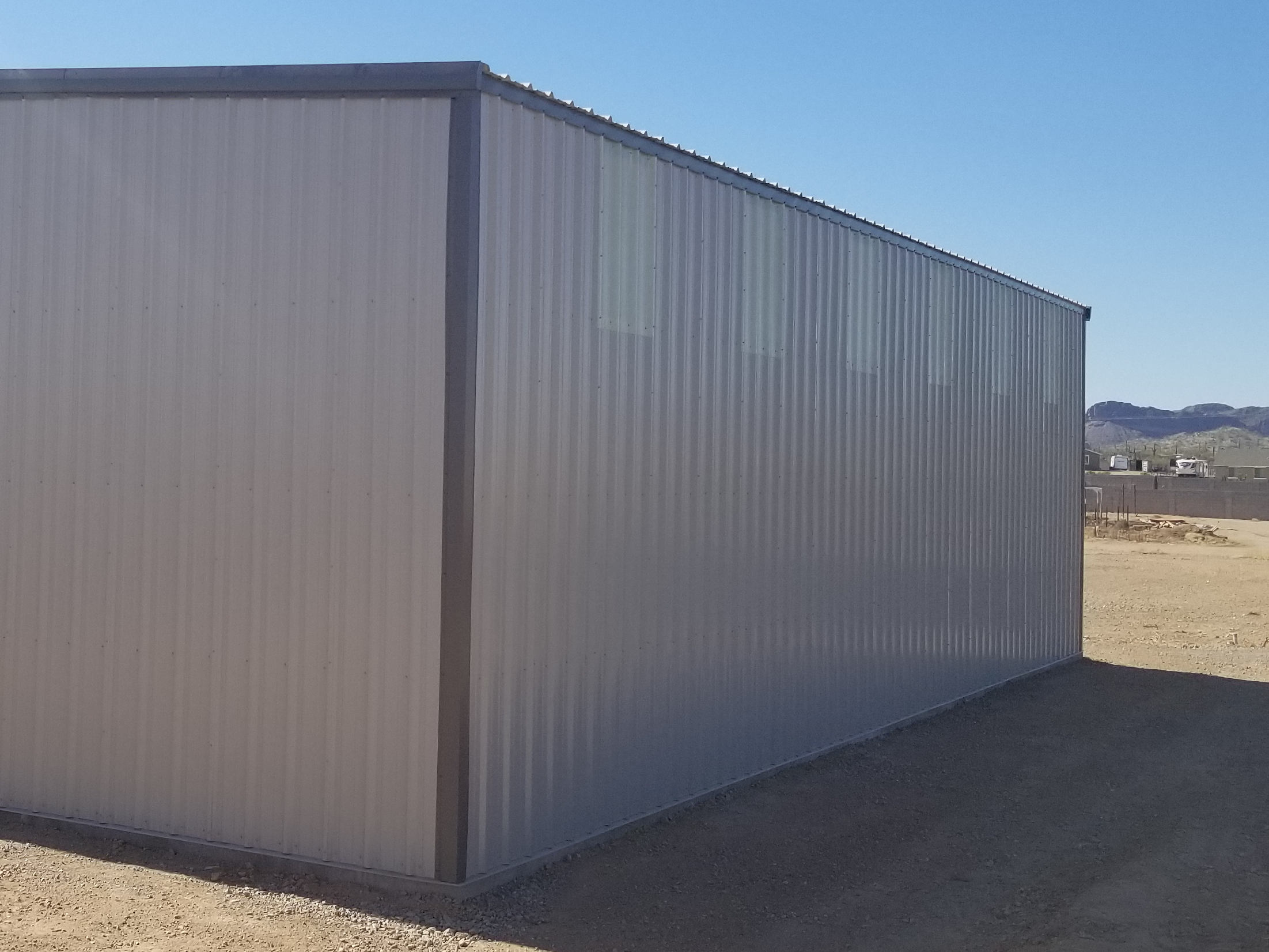 Showing the exterior of a steel building with translucent sheeting high up on an exterior wall. Emphasizing the look and quality of translucent pannel as a natural lighting option