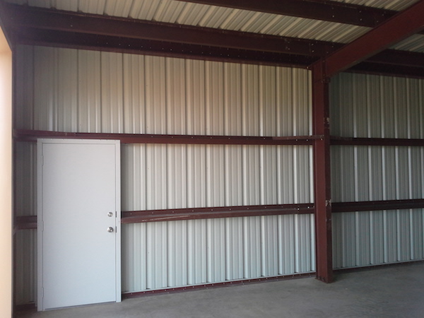 Showing a walk-through door from the interior of a steel building.